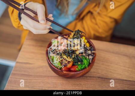 Femme mangeant le bol de poke biologique cru avec du riz et des légumes gros plan sur la table. Vue de dessus horizontale Banque D'Images