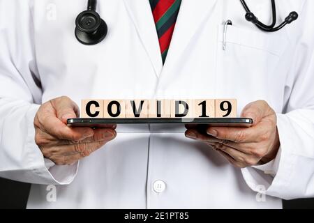 Un médecin de sexe masculin en manteau blanc montrant des blocs de lettres orthographe covid19, comme un avertissement pour le virus corona épidermique qui a récemment officialisé nommé Covid-19 Banque D'Images
