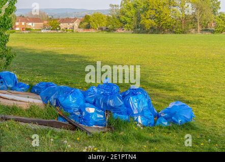 Des déchets en plastique bleu ont été désutilisés à l'aide d'un bout de mouche et ont été illégalement jetés dans un terrain de football public. Stockport Royaume-Uni. Banque D'Images