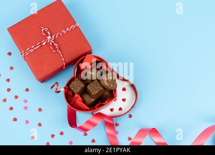 Boîte rouge en forme de coeur ouvert plein de chocolats sur fond bleu. Concept de la Saint-Valentin, anniversaire, fête des mères et anniversaire. COP Banque D'Images