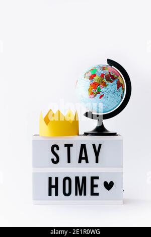 Concept de Covid 19. Texte rester à l'origine affiché dans la visionneuse et le globe avec couronne sur elle, arrière-plan clair. Banque D'Images