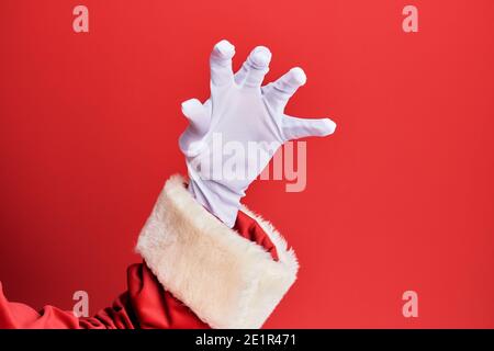 Main d'un homme portant le costume du père noël et des gants sur fond rouge saisissant agressif et effrayant avec les doigts, la violence et la frustration Banque D'Images