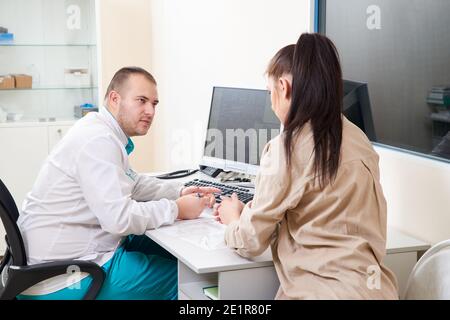 Jeune médecin de sexe masculin examinant et consultant une jeune patiente dans une clinique hospitalière. Médecin généraliste professionnel consultant diagnostic médical Banque D'Images