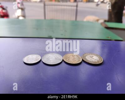 Nouvelles pièces de monnaie indienne de roupies un, deux, cinq et dix gardées sur fond bleu gros plan tourné avec fond de route de rue Banque D'Images
