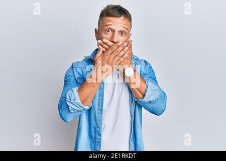 Beau muscle homme portant une veste de denim décontractée choqué couvrant la bouche avec les mains pour erreur. Secret concept. Banque D'Images