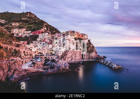 ITALIE, COUCHER DE SOLEIL À MANAROLA: Manarola, hameau de Riomaggiore, est un joyau de l'urbanisme, riche comme il est dans les maisons typiques de la tour de style génovois. Fondé au XIIe siècle, le village tire probablement son nom d'une ancienne 'magna roea', une grande roue de moulin présente dans le village. Banque D'Images