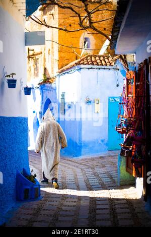 (Attention sélective) UN homme, portant la Djellaba ou la Jillaba, se promène dans les rues de la ville bleue de Chefchaouen, au Maroc. Banque D'Images