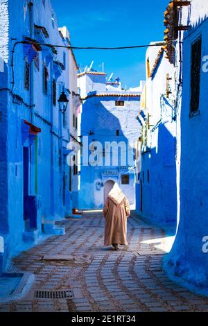 (Attention sélective) UN homme, portant la Djellaba ou la Jillaba, se promène dans les rues de la ville bleue de Chefchaouen, au Maroc. Banque D'Images