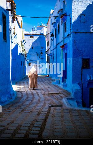 (Attention sélective) UN homme, portant la Djellaba ou la Jillaba, se promène dans les rues de la ville bleue de Chefchaouen, au Maroc. Banque D'Images