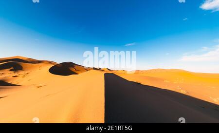 (Mise au point sélective) vue imprenable sur quelques dunes de sable illuminées au coucher du soleil. Merzouga, Maroc. Arrière-plan naturel avec espace de copie. Banque D'Images
