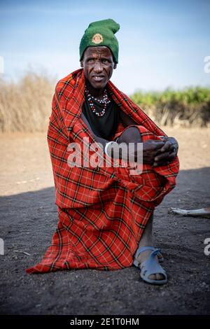 Ancien homme de Datoga assis à l'extérieur de sa maison dans des vêtements traditionnels Banque D'Images