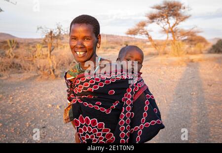 Lac Eyasi, Arusha, Tanzanie, 04 octobre 2020 : jeune femme de datoga portant son petit garçon sur le chemin du retour du puits où elle était en train de récupérer wat Banque D'Images
