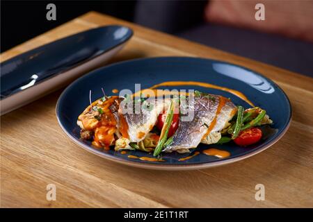 Fruits de mer. Dorada cuit avec des légumes à la sauce aux crevettes sur la table, servant dans un restaurant, concept de menu Banque D'Images