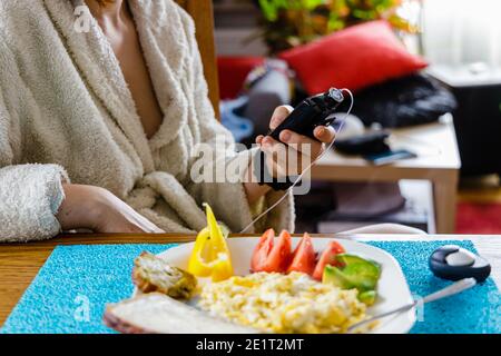 Traitement moderne du diabète, femme vérifiant le niveau de glucose et doser l'insuline avec pompe à insuline avant son petit déjeuner sain Banque D'Images