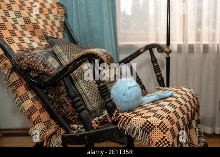 Intérieur de maison vintage, un vieux fauteuil à bascule avec une couverture populaire et une boule de fil Banque D'Images