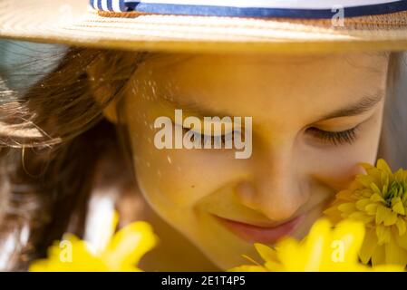 Fille souriante dans un chapeau de paille avec des fleurs jaunes gros plan. Le concept d'un style de vie joyeux Banque D'Images