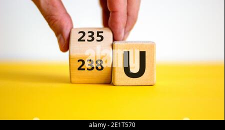 Symbole d'enrichissement d'uranium. La main fait tourner le cube et change le mot « 238 U » en « 235 U ». Magnifique fond jaune, blanc, espace de copie. Affaires, nucl Banque D'Images