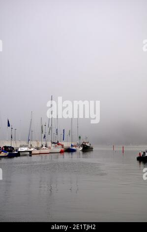 Yachts amarrés sur la jetée de la ville pendant un temps brumeux Banque D'Images