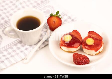 expresso blanc de tasse de café avec des fraises et des fleurs violettes sur une table prête pour le petit déjeuner des pâtisseries italiennes Banque D'Images