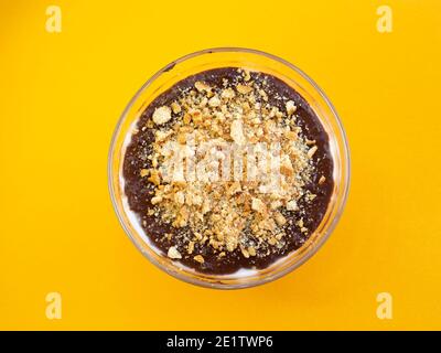 bol en verre de crème au chocolat ou de chocolat fondu et morceaux de chocolat sur fond jaune Banque D'Images