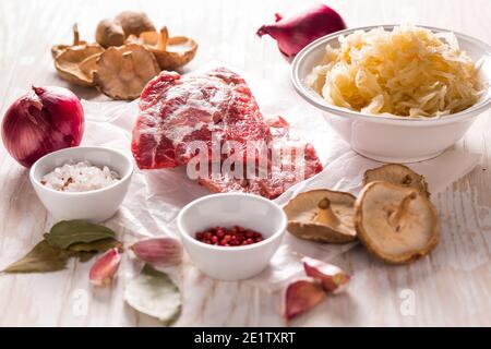 Ingrédients pour une soupe au chou aigre (soupe à la choucroute) avec de la viande, de l'onioc, de l'ail et des épichies sur une table en bois Banque D'Images