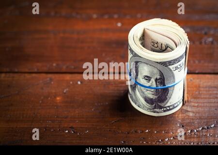 Rouleau d'argent avec du caoutchouc sur une table en bois - une centaine de billets américains avec le portrait du président Franklin. Espèces de billets de cent dollars, papier monnaie ba Banque D'Images