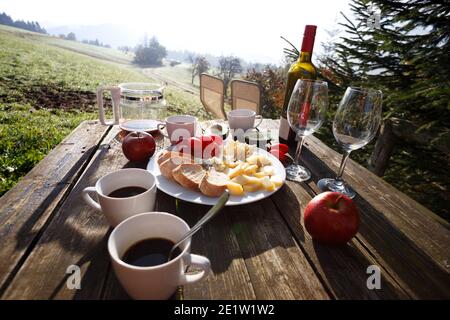 Picnicin sur une ferme. matin dans les montagnes. fromages, pain, tomates, avocat, café sur une table en bois Banque D'Images