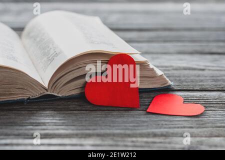 deux coeurs en papier rouge et livre ouvert sur une table en bois Banque D'Images