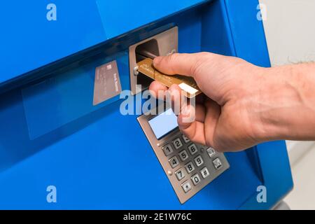 La main du gars insère une carte bancaire dans un guichet automatique, gros plan. Banque D'Images