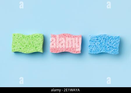 Disposition créative avec éponges pour le lavage de la vaisselle sur fond bleu. Banque D'Images