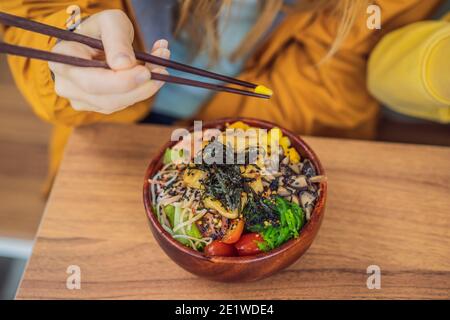 Femme mangeant le bol de poke biologique cru avec du riz et des légumes gros plan sur la table. Vue de dessus horizontale Banque D'Images