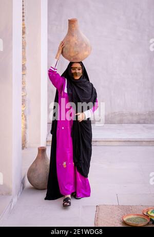 Emarati dame dans des vêtements traditionnels tenant un pot sur elle rendez-vous et partez en roaming dans la maison Banque D'Images