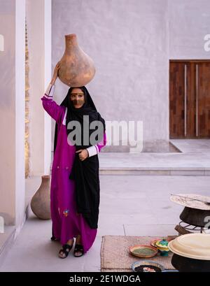 Emarati dame dans des vêtements traditionnels tenant un pot sur elle rendez-vous et partez en roaming dans la maison Banque D'Images