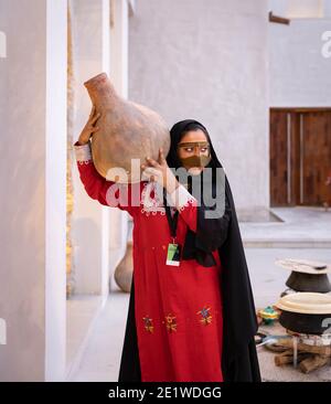 Emarati dame dans des vêtements traditionnels tenant un pot sur elle rendez-vous et partez en roaming dans la maison Banque D'Images