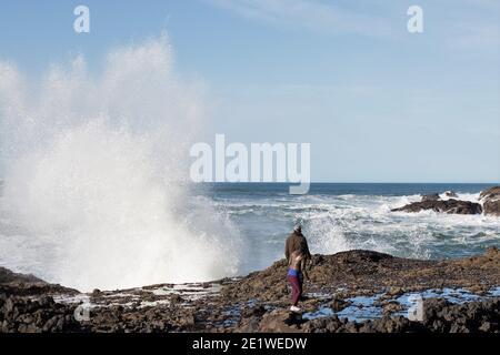 Un couple regardant une énorme vague s'écraser sur les rochers près de Yachats, Oregon. Banque D'Images