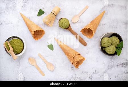 Crème glacée au thé vert Matcha avec cornet de gaufres et feuilles de menthe sur fond de pierre blanche . Concept de menu été et sucré. Banque D'Images