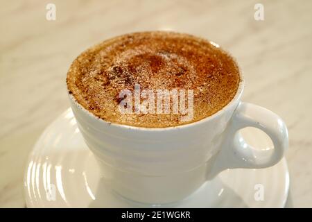 Tasse de cappuccino mousseux isolée sur une table blanche Banque D'Images