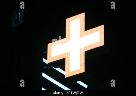 Croix de pixels lumineuse des lampes LED sur fond noir. Croix orange avec centre blanc symbole de santé, médecine, autosoins. Photo de stock avec spa vide Banque D'Images