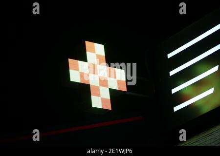 Croix de pixels lumineuse des lampes LED sur fond noir. Croix avec un motif en blanc et orange carré symbole de la santé, de la médecine, de l'auto-soins. Stock pho Banque D'Images