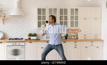 Un jeune homme souriant fait de la danse dans la cuisine Banque D'Images