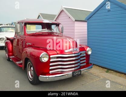 Pick-up Classic Red Chevrolet 3100 sur la promenade du front de mer, devant les cabines de plage. Banque D'Images