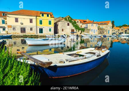 Excellente destination de voyage et de vacances. Village touristique et de pêche avec maisons en pierre reflétées sur la mer. Bateaux de pêche amarrés dans la villa de Vrboska Banque D'Images