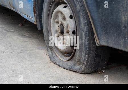 Un vieux pneu crevé d'une vieille voiture rouillée. Vue latérale. Mise au point sélective. Banque D'Images