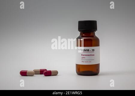 Petite bouteille de pilule / flacon (flacon) avec une étiquette qui Lit 'Covid - 19 comprimés de virus Corona pour usage oral Isolé sur fond blanc médecine pour prévenir Banque D'Images
