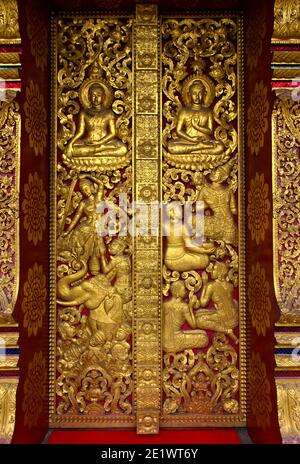 Portail d'entrée avec des sculptures dorées représentant des créatures mythiques et des scènes de la vie de Bouddha, Temple Wat Nong Sikhounmuang, Luang Prabang, Laos Banque D'Images