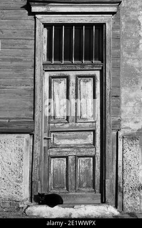 Chat noir dort sur un seuil de la vieille maison en bois. Banque D'Images