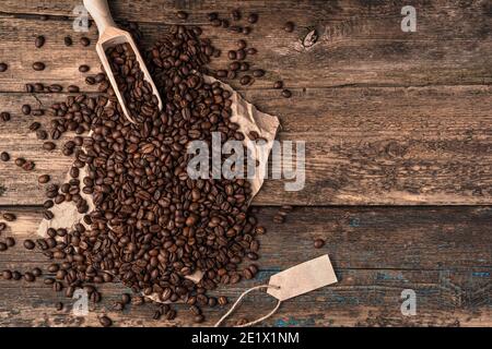 Verser les grains de café dans un sac de lin et une spatule en bois sur un fond blanc. Banque D'Images