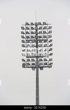 Projecteur de stade avec poteau métallique, mât d'éclairage, tour avec projecteurs dans le stade de sport contre le ciel blanc Banque D'Images