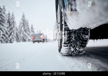 Vue rapprochée du pneu de la voiture sur route enneigée et glacée. Thèmes sécurité et conduite en hiver. Banque D'Images