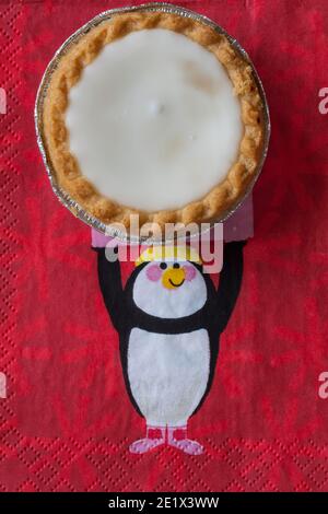 Tarte aux pommes de terre hachée glacée de Sainsburys sur une serviette de Noël festive - pâtisseries fourrées de viande hachée, recouvertes de glaçage blanc doux Banque D'Images